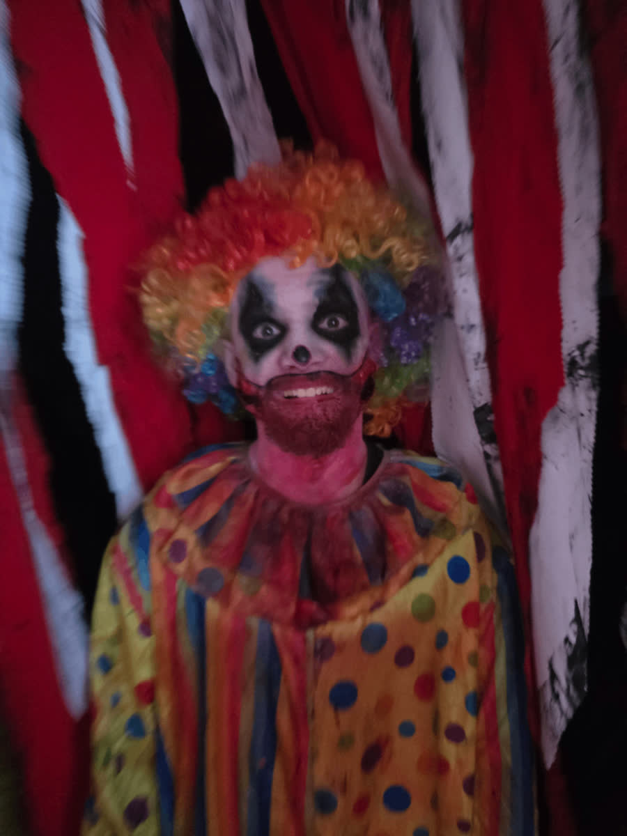 A costumed haunted-house performer in clown makeup.